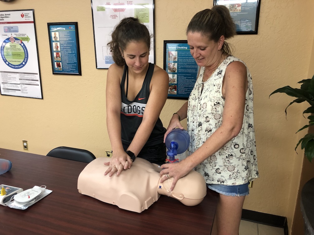 woman and young girl doing basic cpr on mannequin