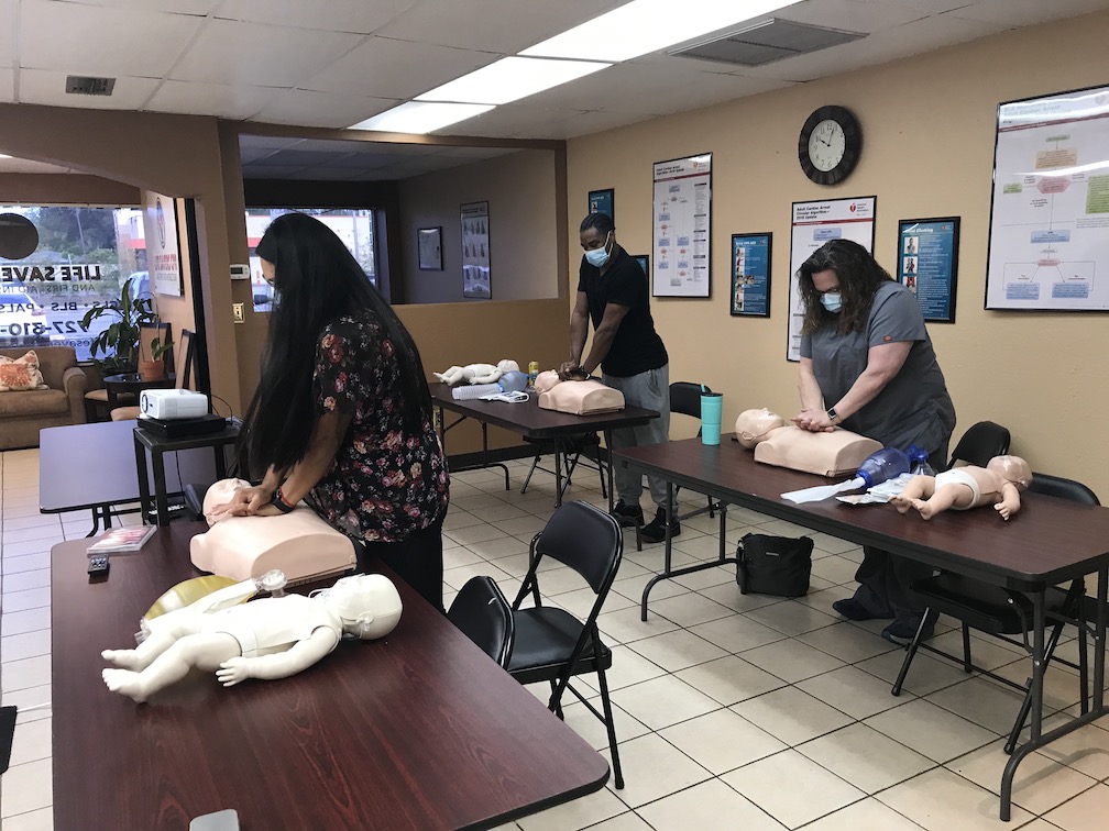 two saint petersburg women and man doing basic cpr on mannequins