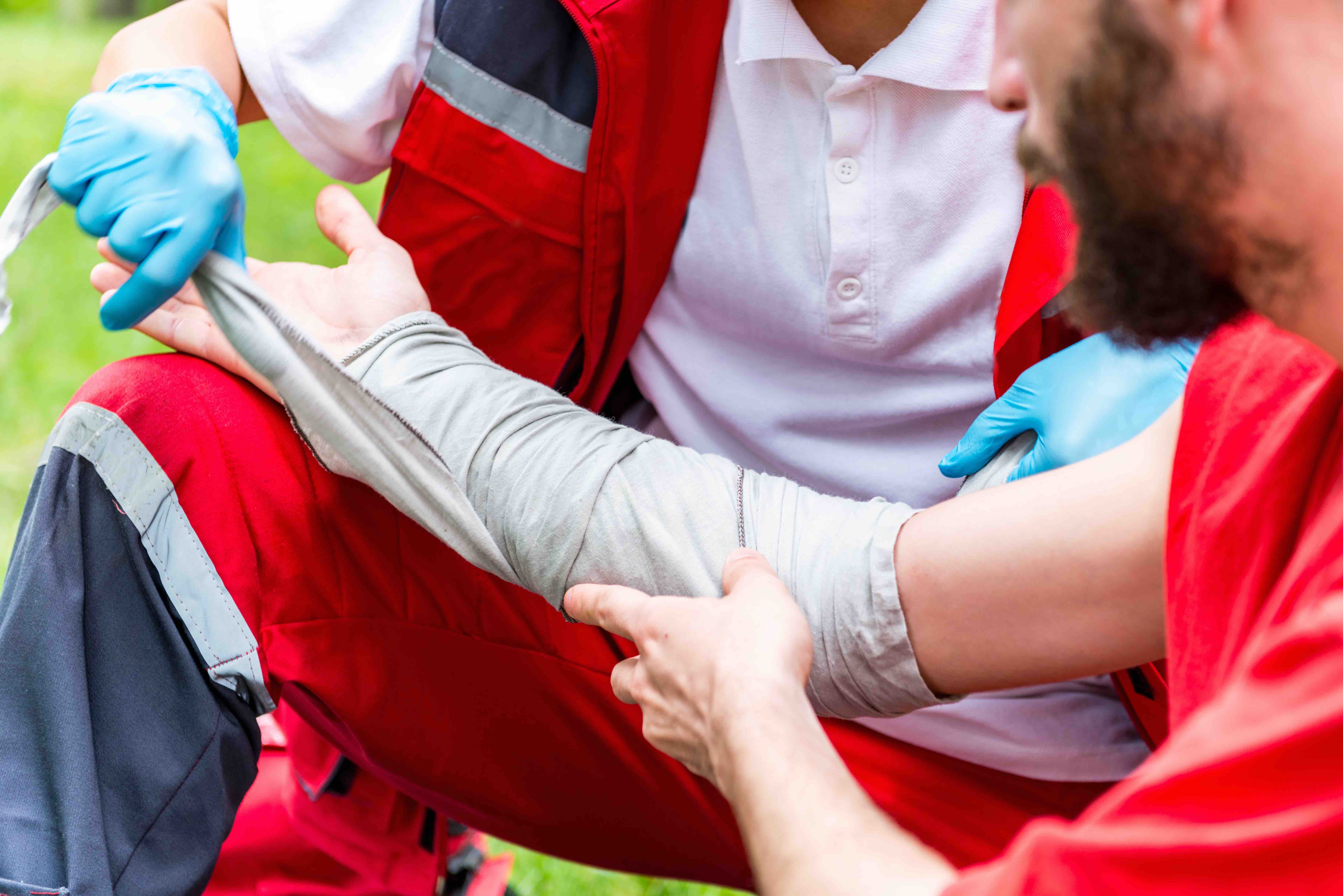 first aid man wrapping mans right arm with first aid sleeve cover